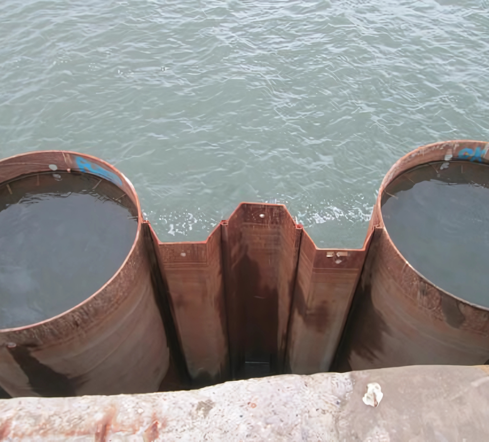 Top-down view of the combi wall system showing two steel pipe piles with an intermediate triple U sheet pile between them.