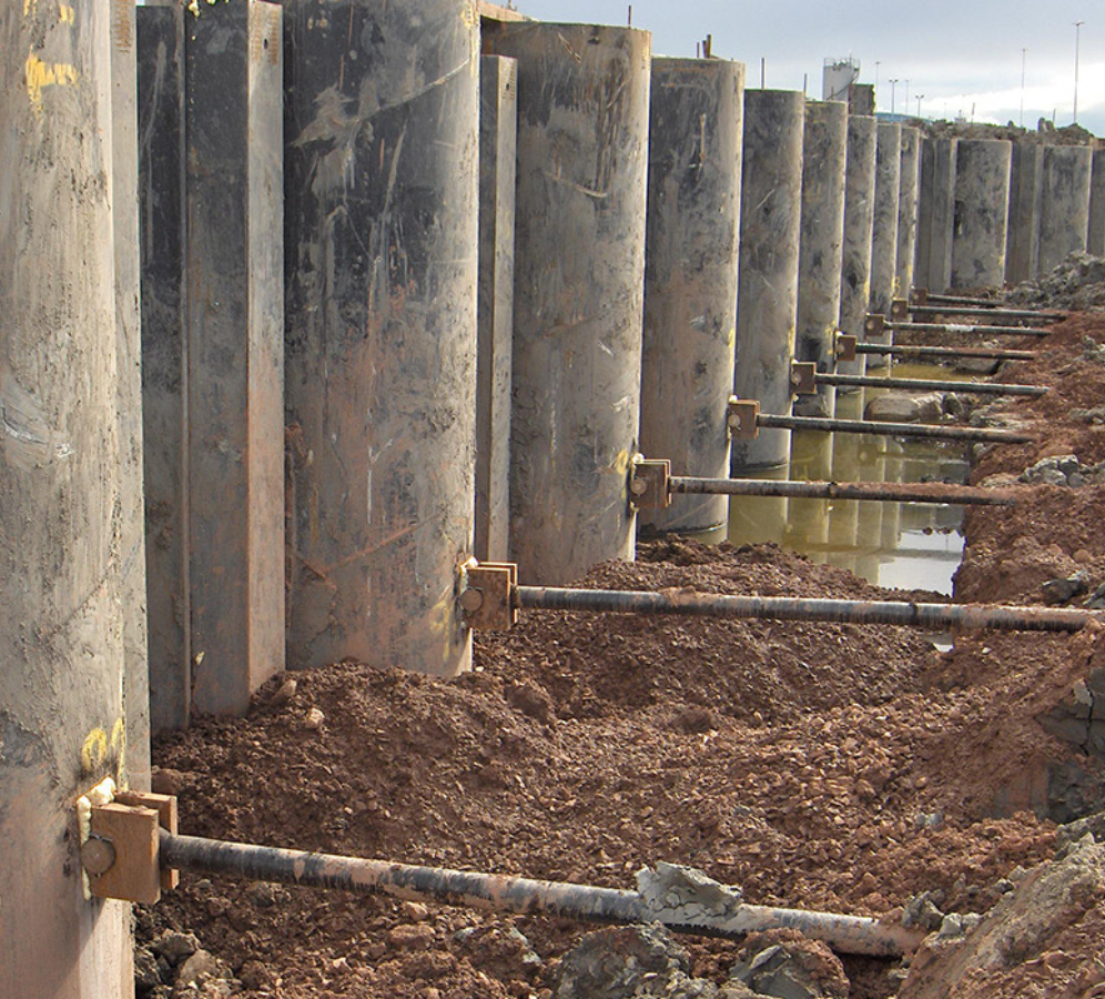 Combi wall with pipe piles and Steel sheet piles reinforced with horizontal tie rods, each placed at consistent length intervals to resist normal bending loads in foundation construction