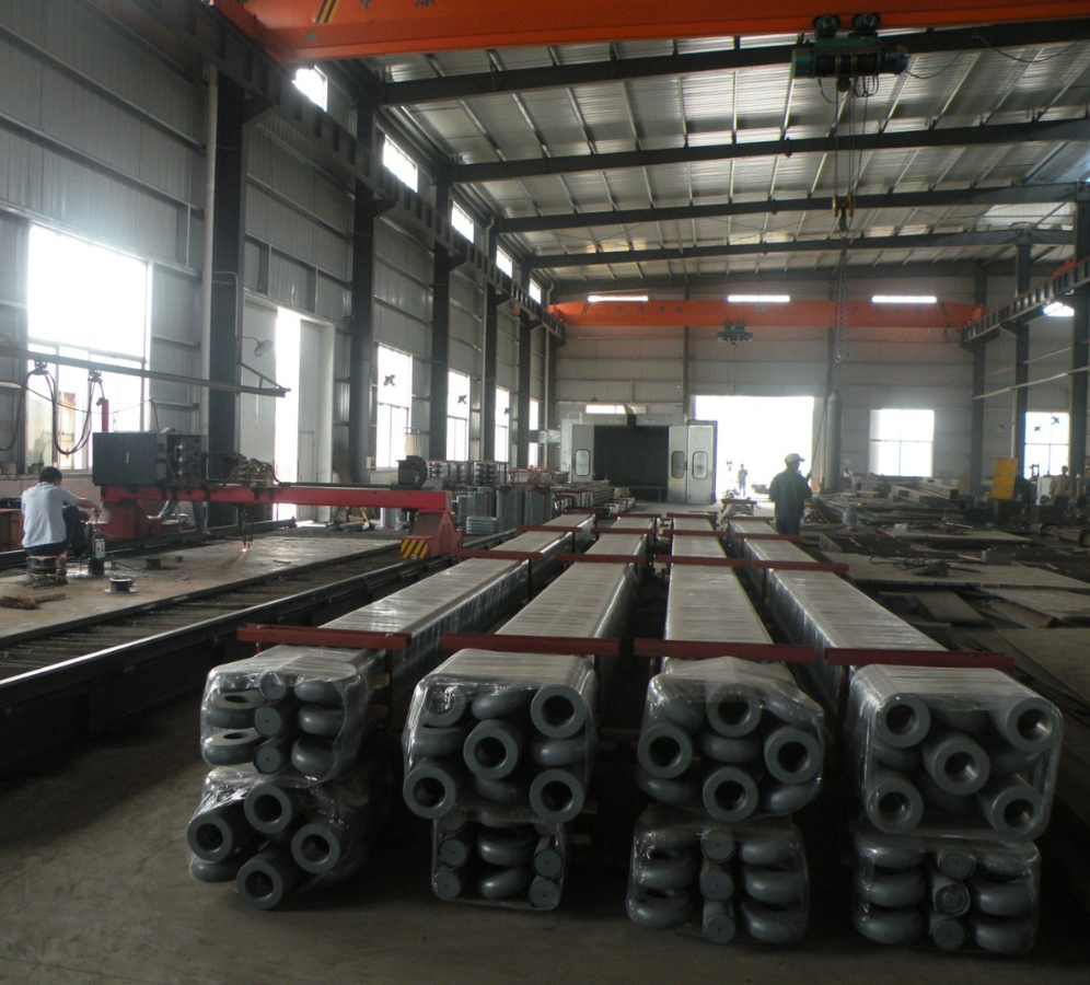 Steel tie rods and end fittings are packed and prepared for shipment in a manufacturing facility, with a technical team in the background, ready for use in marine or infrastructure projects.