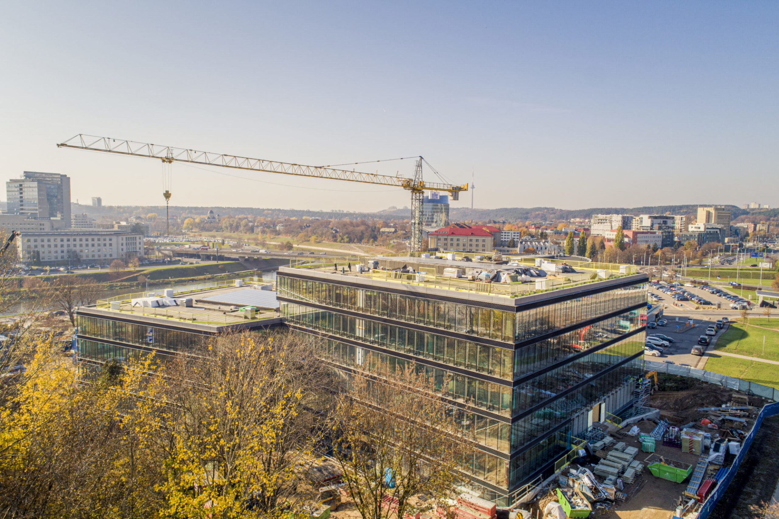 Post Tension Commercial Building Projekt Fertiggestelltes Geschäftsgebäude aus Spannbeton mit moderner Glasfassade, umgeben von städtischer Landschaft und einem Turmkran im Hintergrund.