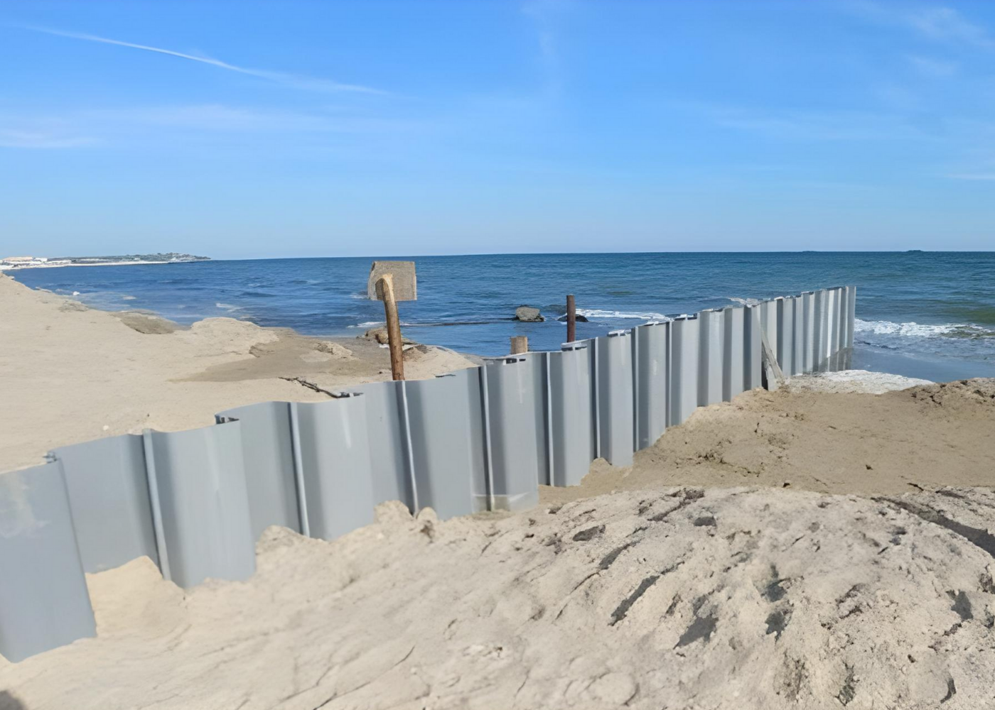 A vinyl sheet pile retaining wall installed on a sandy beach for coastal erosion protection.