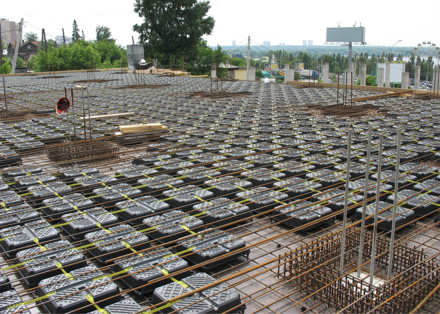 Modular plastic void formers installed between steel reinforcement layers on a concrete slab construction site, showcasing a two-way lightened slab system in progress.