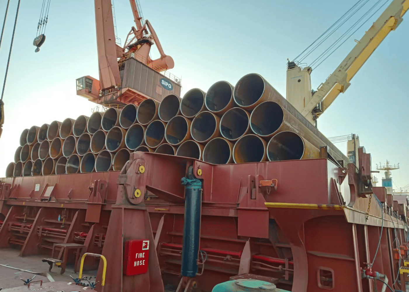 Large-diameter steel pipes loaded onto cargo ship for international delivery.