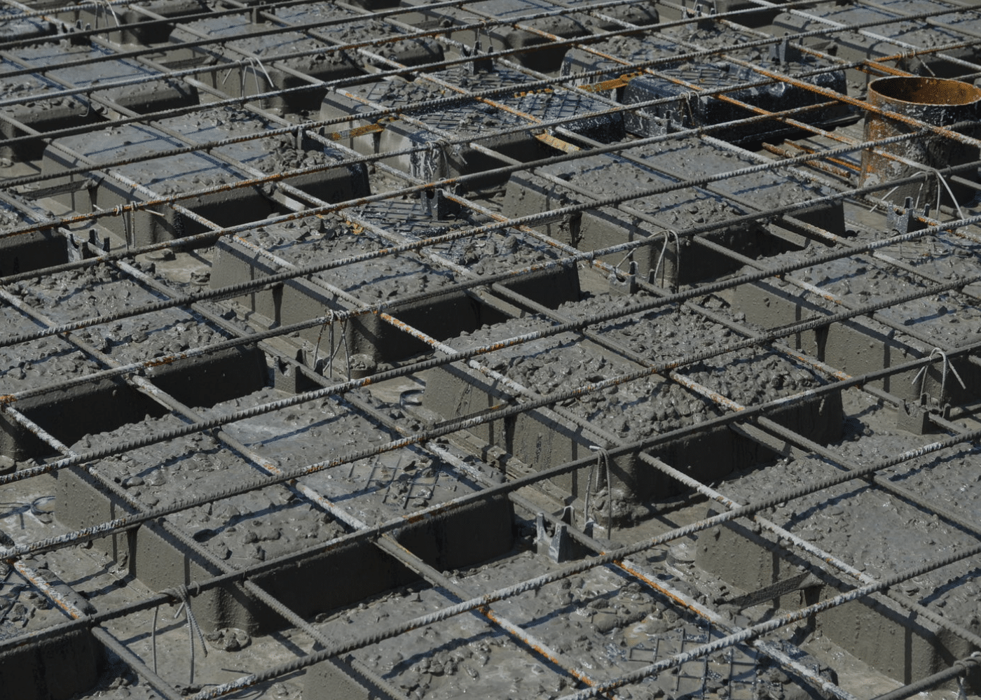 Close-up view of the first-stage concrete pouring process, showing void formers partially embedded within a reinforced slab grid.