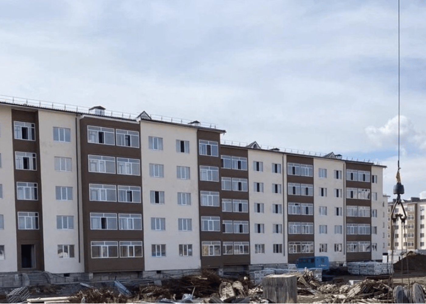 Construction site of a mid-rise residential building with five stories, showcasing the 2nd typical application use-case of void formers, featuring wall-bearing structures and crane equipment in the foreground for material handling.