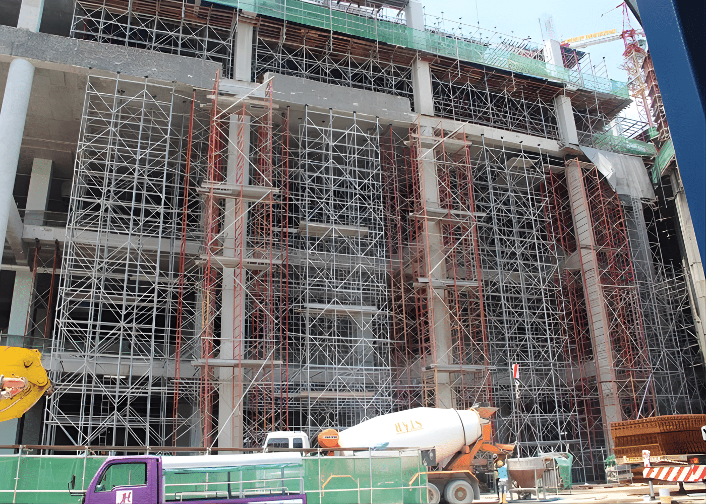 Vähittäiskaupan monimutkainen telineprojekti Rakenteilla olevan teräsbetonirakennuksen julkisivun poikki asennettu suuri monitasoinen teräksinen telinejärjestelmä, jossa näkyy tiheä poikkipalkitus, pystykehykset ja useita kerroksia kattavat kulkutasot.